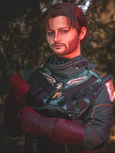 Person dressed as Soldier Boy standing with arms crossed in a wooded setting.